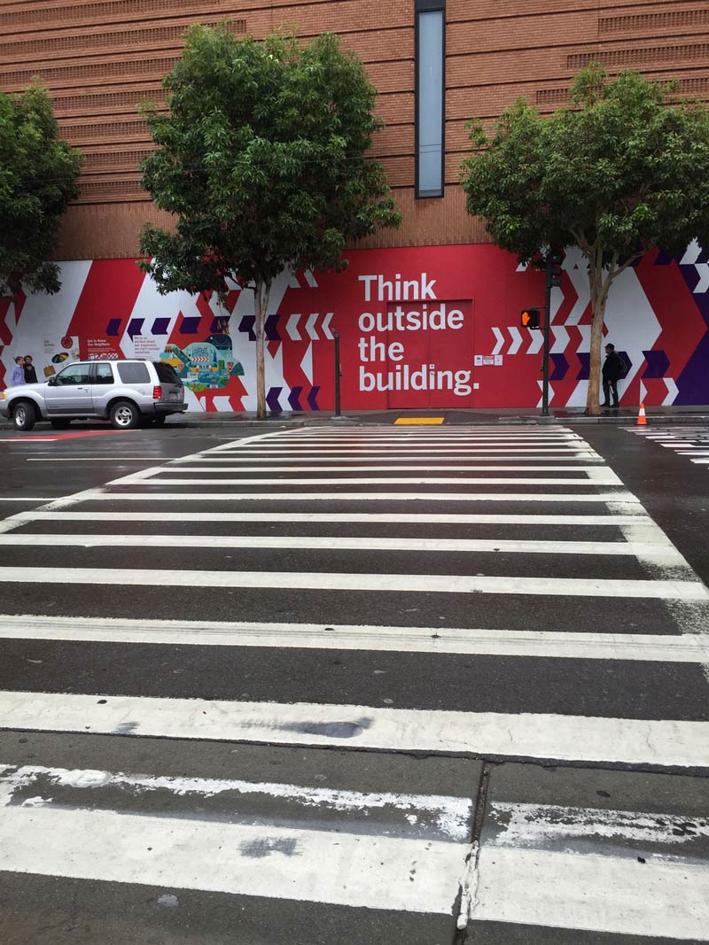 crosswalk shot across from the sfmoma with painting that reads think outside the building.